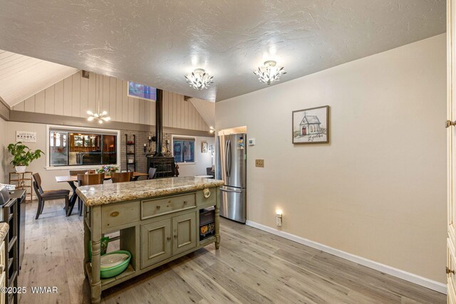 2331 W Rogers Loop, Show Low, AZ 85901 - kitchen with freestanding refrigerator, vaulted ceiling, baseboards, a wood stove, and light wood-style flooring