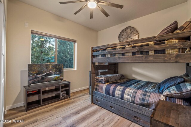 bedroom with a ceiling fan, baseboards, and light wood finished floors