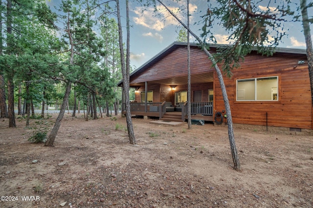 back of property at dusk with crawl space and a porch