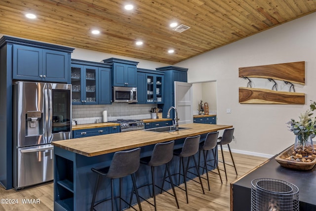 kitchen with open shelves, glass insert cabinets, appliances with stainless steel finishes, wood counters, and blue cabinets