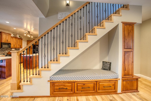 staircase with baseboards and wood finished floors