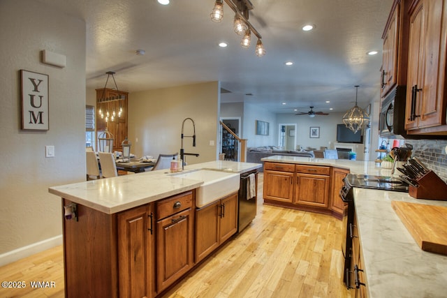 kitchen with black appliances, open floor plan, light wood finished floors, and a sink