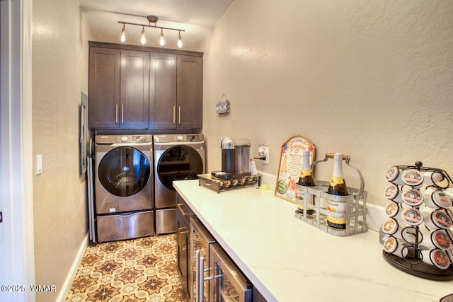 clothes washing area featuring washer and dryer, wine cooler, rail lighting, and cabinet space