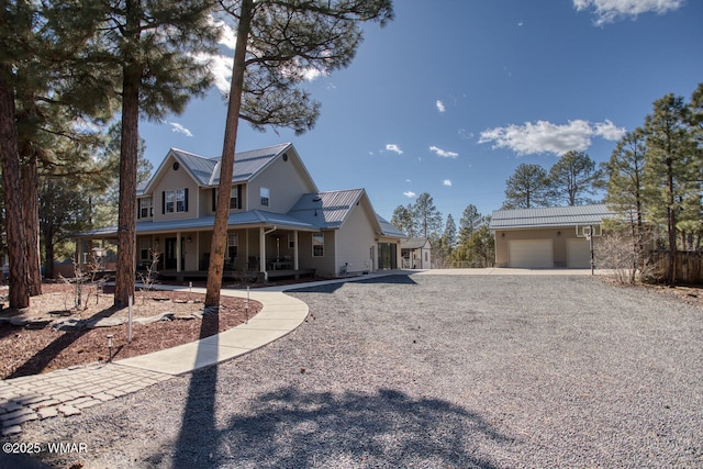 view of front of home with a garage, covered porch, and metal roof