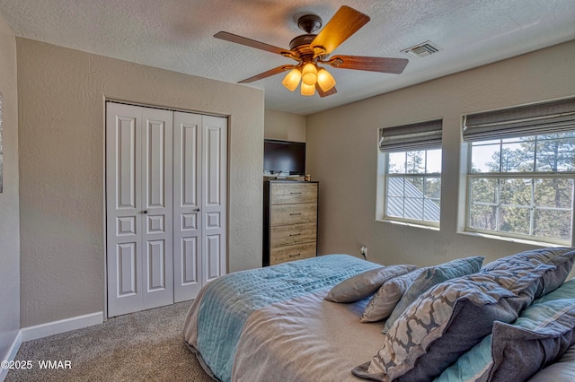 carpeted bedroom with visible vents, a textured ceiling, a closet, baseboards, and a textured wall