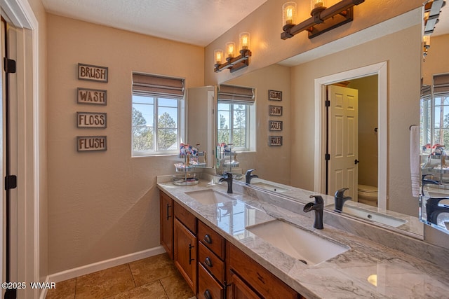 full bath with a sink, baseboards, and double vanity