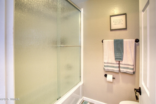 full bathroom with enclosed tub / shower combo, toilet, and baseboards