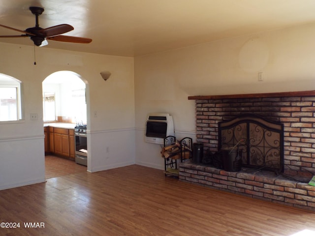 unfurnished living room featuring a brick fireplace, ceiling fan, and wood finished floors