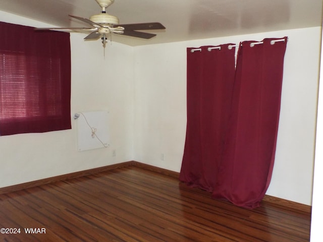 spare room with ceiling fan, baseboards, and dark wood finished floors