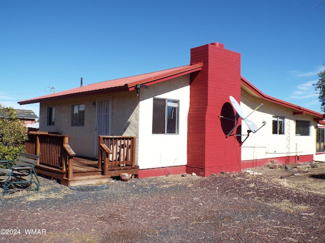 back of property featuring a chimney, metal roof, and a wooden deck