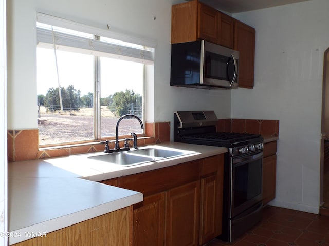 kitchen featuring appliances with stainless steel finishes, light countertops, brown cabinets, and a sink