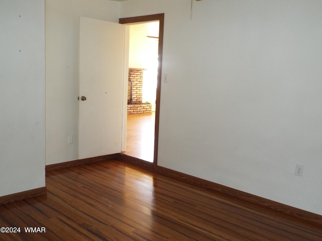 empty room with baseboards and dark wood-type flooring