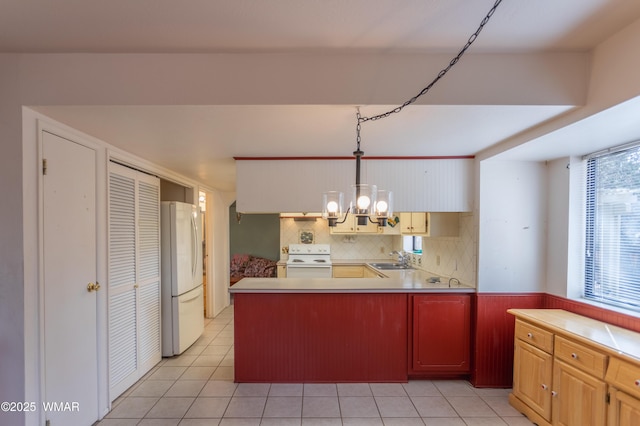 kitchen featuring hanging light fixtures, white appliances, light countertops, and a sink