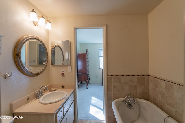 bathroom featuring a textured wall, a soaking tub, and vanity