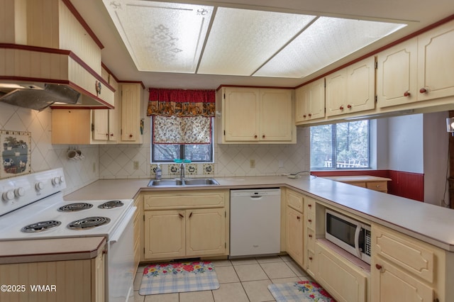 kitchen with light tile patterned flooring, a peninsula, white appliances, a sink, and light countertops