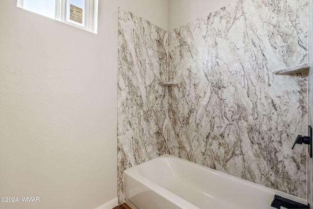 bathroom featuring a bath and baseboards