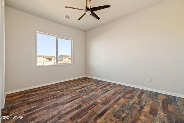 unfurnished room with ceiling fan, dark wood-style flooring, visible vents, and baseboards