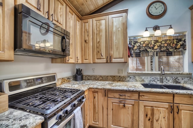 kitchen featuring black microwave, stainless steel gas stove, a sink, and light stone countertops