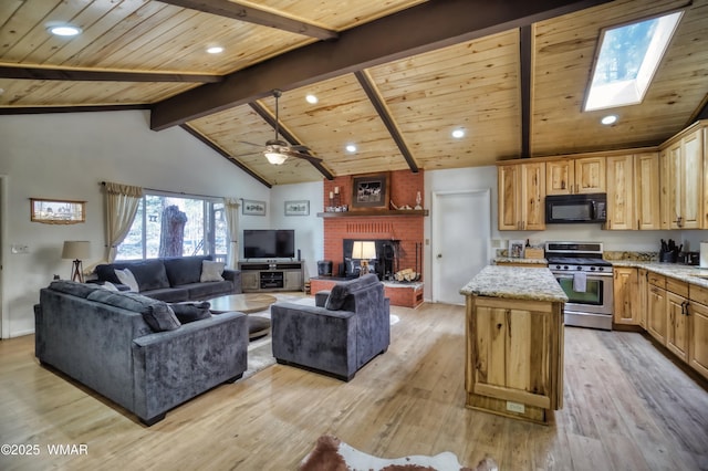 kitchen with stainless steel gas stove, light wood finished floors, a kitchen island, open floor plan, and black microwave