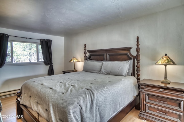 bedroom featuring light wood-type flooring and a baseboard radiator