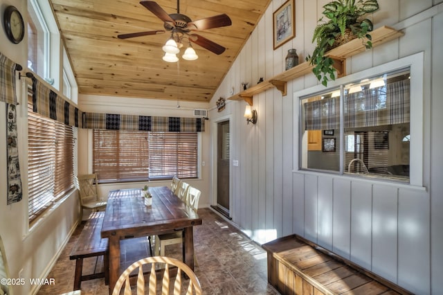 dining space featuring visible vents, vaulted ceiling, wooden walls, ceiling fan, and wooden ceiling