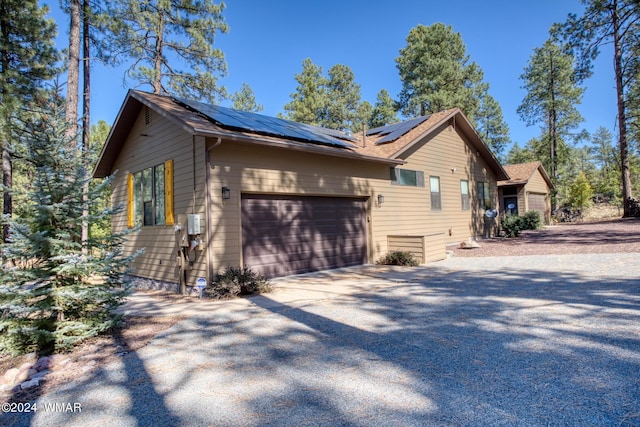 view of side of home featuring roof mounted solar panels, driveway, and an attached garage