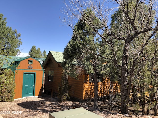view of front of house featuring metal roof, a storage shed, a gambrel roof, and an outbuilding