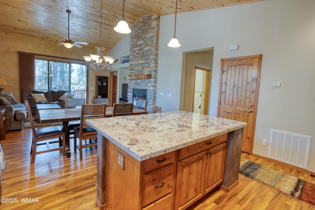 kitchen with brown cabinets, visible vents, open floor plan, and decorative light fixtures