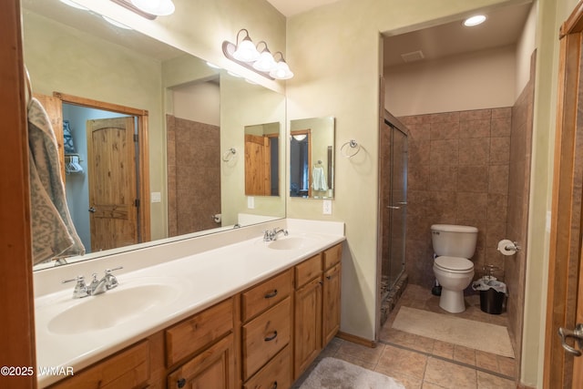 full bathroom with double vanity, toilet, a sink, and tile patterned floors