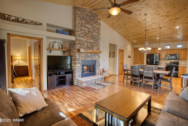 living area featuring high vaulted ceiling, a stone fireplace, ceiling fan with notable chandelier, wood ceiling, and light wood finished floors