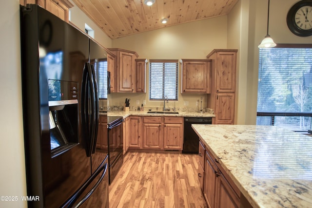 kitchen with brown cabinetry, decorative light fixtures, vaulted ceiling, black appliances, and a sink