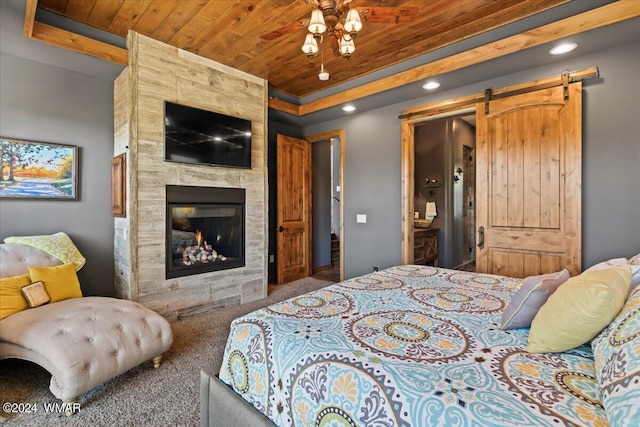 carpeted bedroom with a barn door, a fireplace, wood ceiling, and recessed lighting