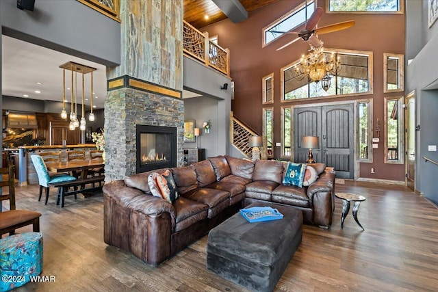 living area featuring wood ceiling, stairway, wood finished floors, a stone fireplace, and beam ceiling