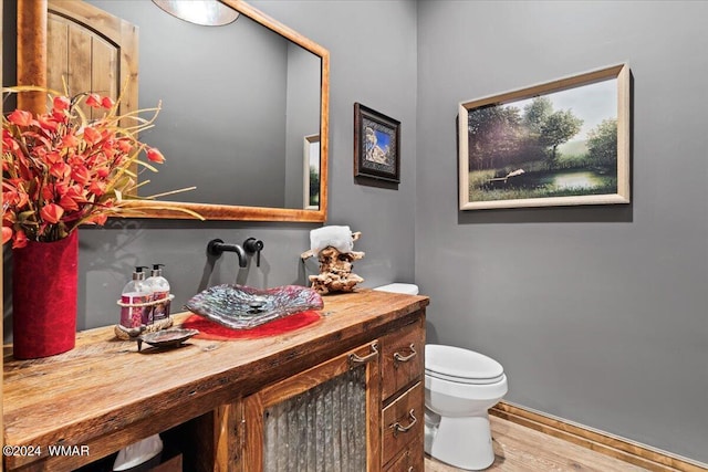 half bathroom with vanity, toilet, and wood finished floors