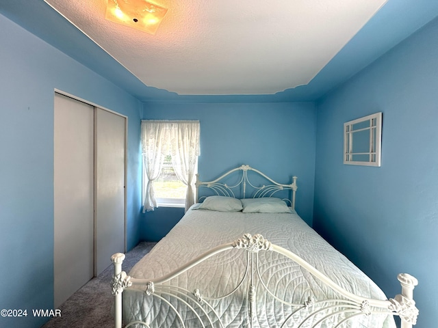 carpeted bedroom featuring a textured ceiling and a closet