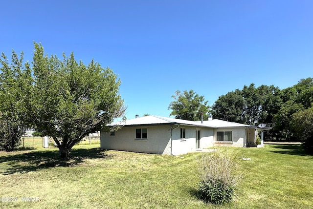 back of house featuring a lawn and stucco siding