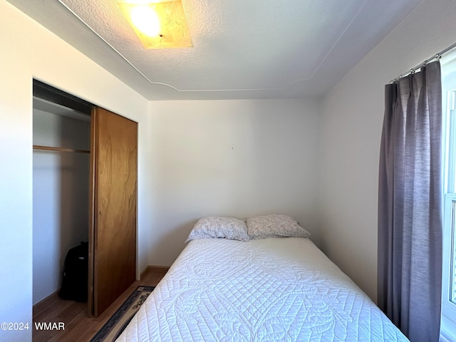 bedroom featuring a textured ceiling, a closet, and wood finished floors