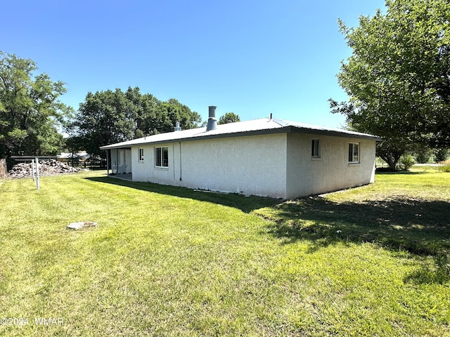 exterior space with metal roof, a lawn, and stucco siding