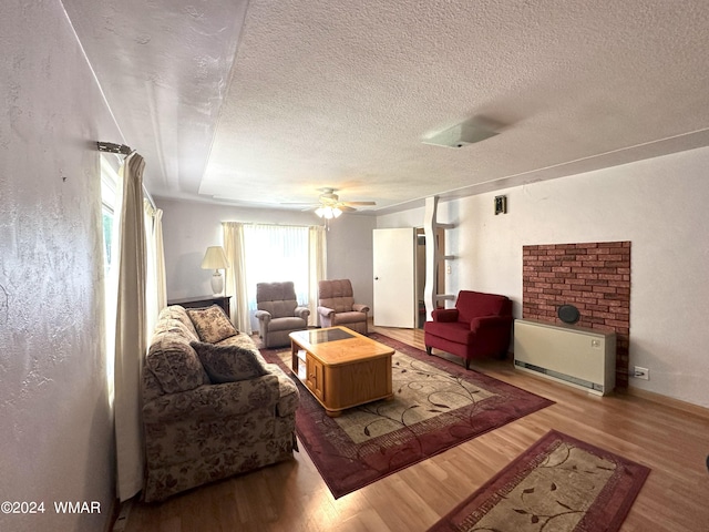 living room featuring light wood-type flooring, ceiling fan, and a textured ceiling