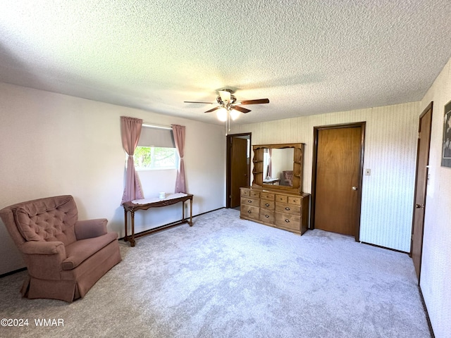 sitting room with wallpapered walls, ceiling fan, a textured ceiling, and light colored carpet