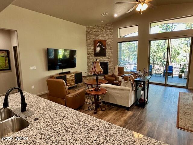 3180 N Eagles Creek Dr, Show Low, AZ 85901 - living room featuring ceiling fan, dark wood-style floors, lofted ceiling, and a stone fireplace