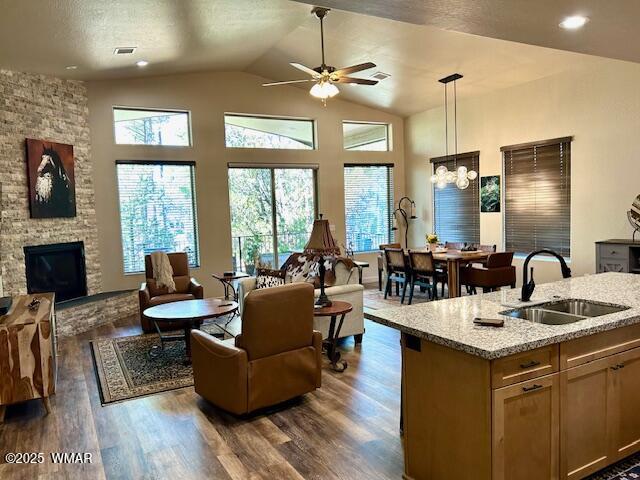 3180 N Eagles Creek Dr, Show Low, AZ 85901 - living room with a ceiling fan, dark wood-type flooring, vaulted ceiling, a fireplace, and a chandelier
