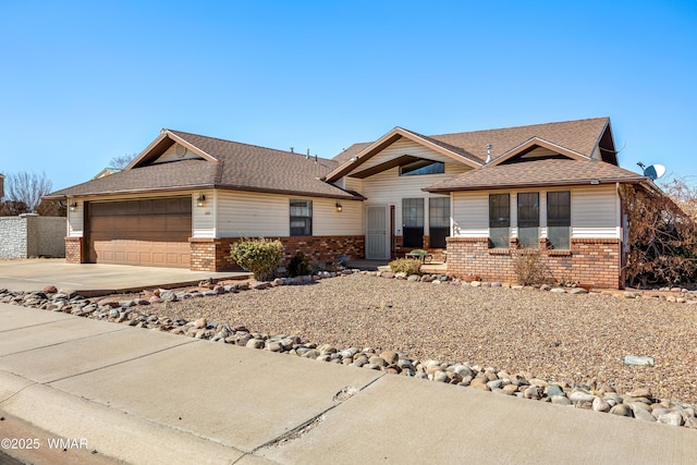 ranch-style home featuring a garage, concrete driveway, brick siding, and roof with shingles