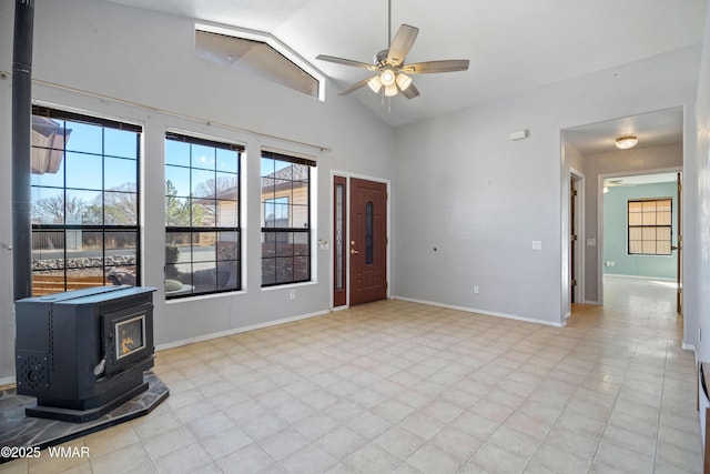 entrance foyer featuring high vaulted ceiling, a wood stove, ceiling fan, and baseboards