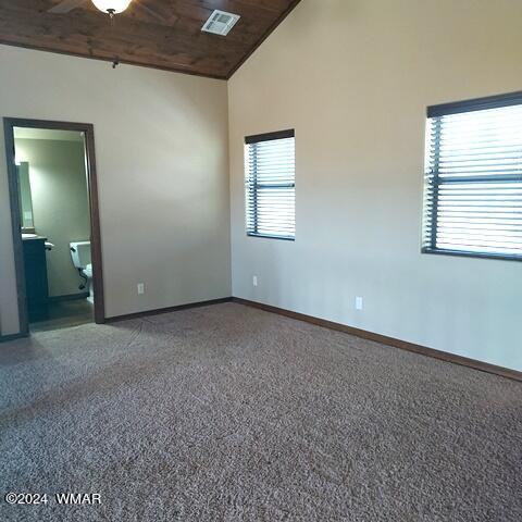 empty room featuring wooden ceiling, baseboards, visible vents, and high vaulted ceiling