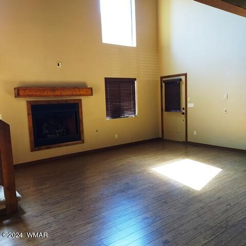 unfurnished living room featuring dark wood-type flooring, a fireplace, and a high ceiling