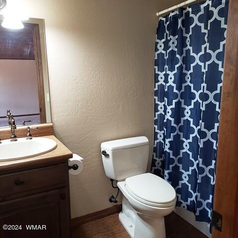 full bath featuring toilet, vanity, and a textured wall