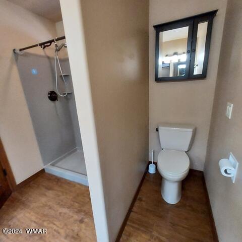 bathroom featuring a stall shower, toilet, and baseboards