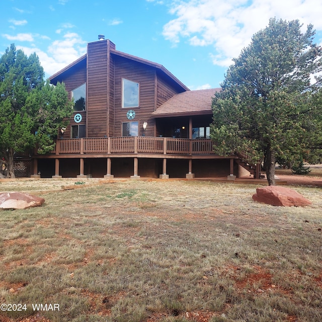 rear view of property with a lawn, a chimney, and a wooden deck