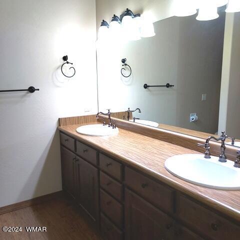 full bathroom with double vanity, a sink, and wood finished floors